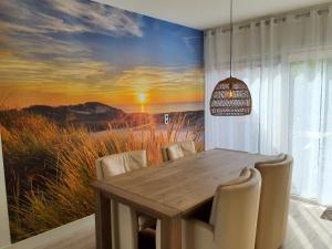 un comedor con una mesa y una pintura de una puesta de sol en Holiday home Happy House, en Noordwijkerhout