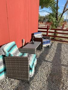 two wicker chairs and a table next to a red wall at Area 3251 Desert Valley Guest Suite in Pahrump