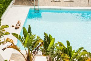 a swimming pool with a person laying on a chair next to it at Hotel Anfora Ibiza in Es Cana