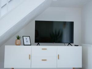 TV en la parte superior de un armario blanco en una habitación en East London House near tube with parking, en Londres