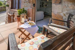 eine Terrasse mit 2 Stühlen und einem Tisch mit Weingläsern in der Unterkunft CASA GERRA COMILLAS in Comillas