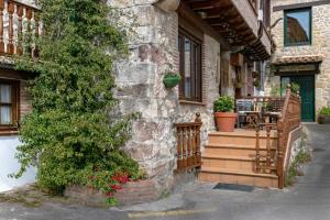 ein Steingebäude mit einer Veranda mit einem Tisch und einem Baum in der Unterkunft CASA GERRA COMILLAS in Comillas