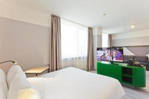 a hotel room with a bed and a flat screen tv at IBIS Styles Kaunas Centre in Kaunas