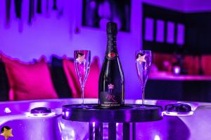a bottle of wine sitting on a table with two glasses at Loveroom Very Good Trip chambre avec jacuzzi privatif in Staple