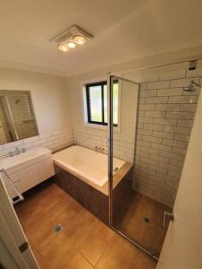 a bathroom with a tub and a sink and a shower at Killara Kottage in Tumut