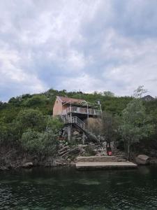 een huis bovenop een heuvel naast een rivier bij Wild Beauty house Skadar lake in Cetinje