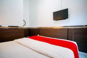 a bed with a red blanket and a tv on the wall at RedDoorz Syariah near Unila in Bandar Lampung