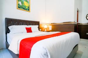 a bedroom with a large bed with a red pillow at RedDoorz Syariah near Unila in Bandar Lampung