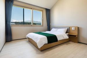 a bedroom with a bed and a large window at Nobhillstay Jeju in Jeju