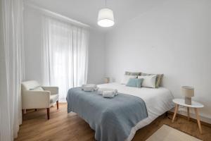 Un dormitorio blanco con una cama grande y una silla. en Apartamento Típico - Vila Mafra, en Nazaré