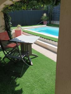 una mesa y una silla junto a la piscina en MimiLou rez-de-jardin avec piscine & spa en Agde