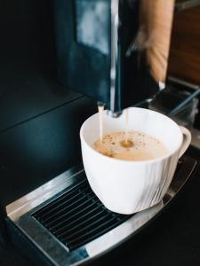 a cup of coffee is being brewed in a microwave at Apartamenty Blisko Słońca in Nowy Targ