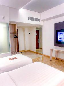 a hotel room with two beds and a flat screen tv at Harper Palembang by ASTON in Palembang