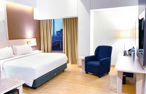 a hotel room with a bed and a blue chair at Harper Palembang by ASTON in Palembang