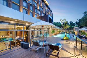 una terraza al aire libre de un edificio con sillas y sombrilla en Sima Sumba Hotel 