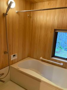 La salle de bains est pourvue d'une baignoire et d'une fenêtre. dans l'établissement Casa KitsuneAna The Satoyama experience in a Japanese-style modernized 100-year-old farmhouse, à Akaiwa