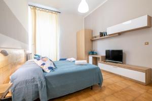 a bedroom with a blue bed and a television at Travel Station Apartment by Pleiades Home in Livorno