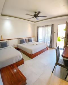 a bedroom with two beds and a desk with a ceiling fan at Yellow Mango Resort Bohol in Panglao Island