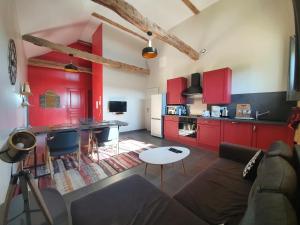 sala de estar con sofá y cocina con armarios rojos. en Le Clos de la Canéda, en Sarlat-la-Canéda
