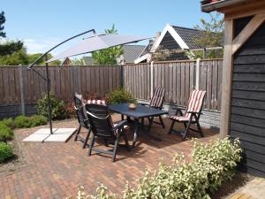 a patio with a table and chairs and an umbrella at Appartement ,Vakantiewoning, Koddelaan 29 in Zoutelande
