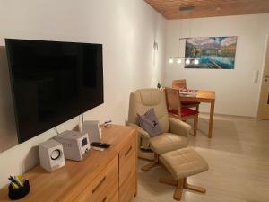 ein Wohnzimmer mit einem TV, einem Stuhl und einem Tisch in der Unterkunft Ferienwohnung Moritz in Oy-Mittelberg