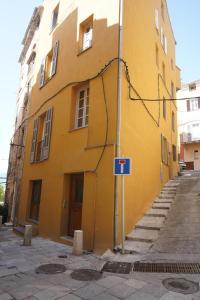 un bâtiment jaune avec un panneau bleu devant lui dans l'établissement Appartement cosy proche de la citadelle, à Bastia