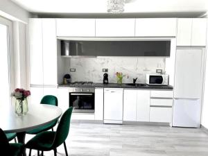 a kitchen with white cabinets and a table with green chairs at Studio Philip by Alezzii Nord 10 in Năvodari