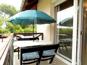 d'une table et de chaises avec un parasol bleu sur le balcon. dans l'établissement 58 - Hullám Üdülőparkban vízközeli modern stúdió apartman, à Balatonőszöd