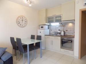 une cuisine avec une table et des chaises et une horloge au mur dans l'établissement 58 - Hullám Üdülőparkban vízközeli modern stúdió apartman, à Balatonőszöd