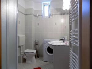 une salle de bains blanche avec toilettes et lavabo dans l'établissement 58 - Hullám Üdülőparkban vízközeli modern stúdió apartman, à Balatonőszöd
