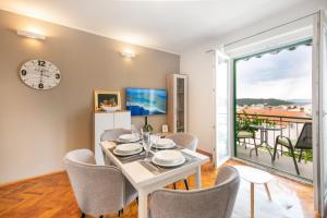 a dining room with a table and chairs and a clock at Apartments Villa Luce in Makarska