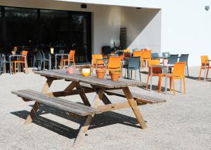 a wooden picnic table with orange chairs and tables at First Inn Hotel Blois in Blois