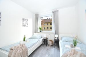 a white bedroom with two beds and a window at CO05-HI Apartment in Coburg in Coburg