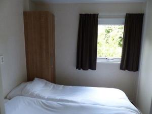 1 dormitorio con cama blanca y ventana en Mobilheim für 5 Personen ca 35 qm in Baarle-Nassau, Nordbrabant en Baarle-Nassau