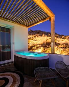 a hot tub on a patio with two chairs at Vrachos Suites Mykonos in Mikonos