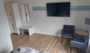 ein Wohnzimmer mit einem Tisch, einem Stuhl und einem TV in der Unterkunft Ording Beach Hotel in Sankt Peter-Ording