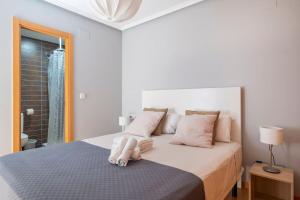 een witte slaapkamer met een groot bed met roze kussens bij Mi pequeña bahia in Alicante