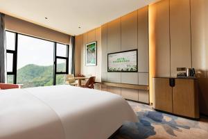 - une chambre avec un grand lit blanc et un bureau dans l'établissement Wyndham Garden Gaozhou, à Gaozhou