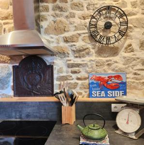 a kitchen with a stone wall with a clock on the wall at L'écurie Kerdoel in Cléder
