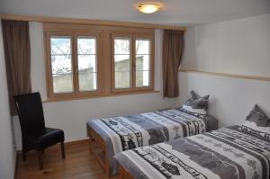 - 2 lits dans une chambre avec une chaise et une fenêtre dans l'établissement Ferienwohnung im Chalet Adelheid, à Grindelwald