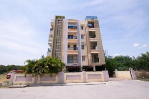 un edificio alto con palme di fronte di High Point Serviced Apartment a Tiruchchirāppalli
