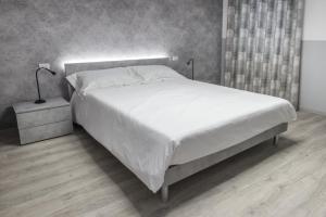 um quarto com uma grande cama branca e uma mesa de cabeceira em PETIT AFFITTACAMERE em Loreto