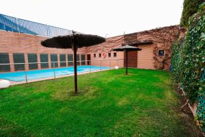 un patio con 2 sombrillas y una piscina en Hotel Reston Valdemoro, en Valdemoro