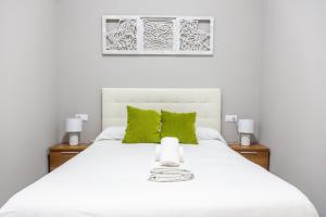 ein Schlafzimmer mit einem weißen Bett mit grünen Kissen in der Unterkunft Apartamento Barrocal by Cadiz Time in Cádiz