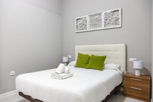 - une chambre avec un lit blanc et des oreillers verts dans l'établissement Apartamento Barrocal by Cadiz Time, à Cadix