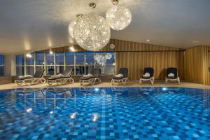eine Hotellobby mit einem Pool, Stühlen und Kronleuchtern in der Unterkunft Maritim Hotel München in München