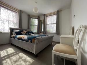 um quarto com uma cama, uma cadeira e janelas em SOUTH COAST ROOM WITH PARKING SPACE NEAR THE BEACh em Poole