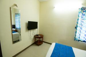Habitación con cama, TV y espejo. en High Point Serviced Apartment, en Tiruchchirāppalli