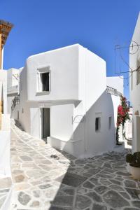 a white building on a street with a stone sidewalk at Rina Houses in Kampos Paros