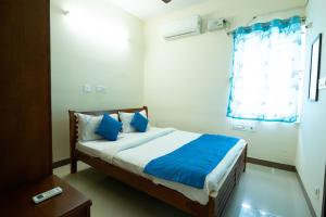 ein Schlafzimmer mit einem Bett mit blauen Kissen und einem Fenster in der Unterkunft High Point Serviced Apartment in Tiruchchirāppalli
